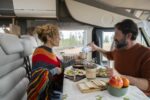 Adult couple enjoy time eating inside camper van in mountain hol