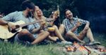 Group of friends camping and sitting around camp fire