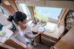 Woman cooking in camper, motorhome interior