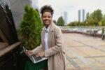 young african american woman working online on laptop outdoors in the city