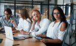 Brunette woman in front of employees. Young business people in formal clothes working in the office