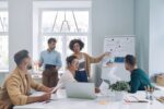 Group of confident young people in smart casual wear discussing business while having meeting in office