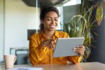 Modern technologies in business. Happy black businesswoman using modern digital tablet, working online in office