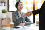 Two Asian businesswomen are shaking hands in the office. business cooperation, business dealing, Congratulations, greeting. close-up hands image