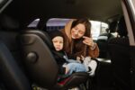 Young mother and child in car. Baby seat on chair. Safety drivin