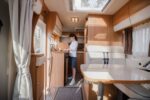 Woman cooking in camper, motorhome interior