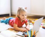 Little girl using computer online technology at home