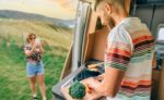 Young man cooking vegetables in a camper van while his wife takes a picture of him with her cell phone