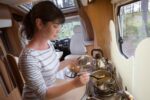 Woman cooking in camper, motorhome interior