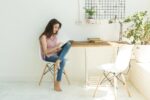 Technologies, communication, people concept – young woman is sitting on chair and chatting in digital tablet and smiling